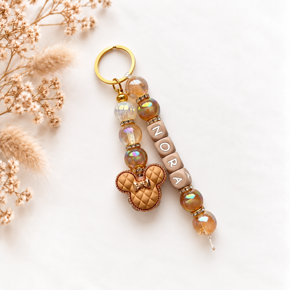 Luxe sleutel- en tassenhanger met naam Nora in champagne- en goudtinten met teddybeer