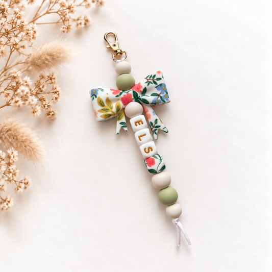 Handgemaakte sleutelhanger met naam Elise, grote bloemenstrik in groen en wit en goudkleurige letters