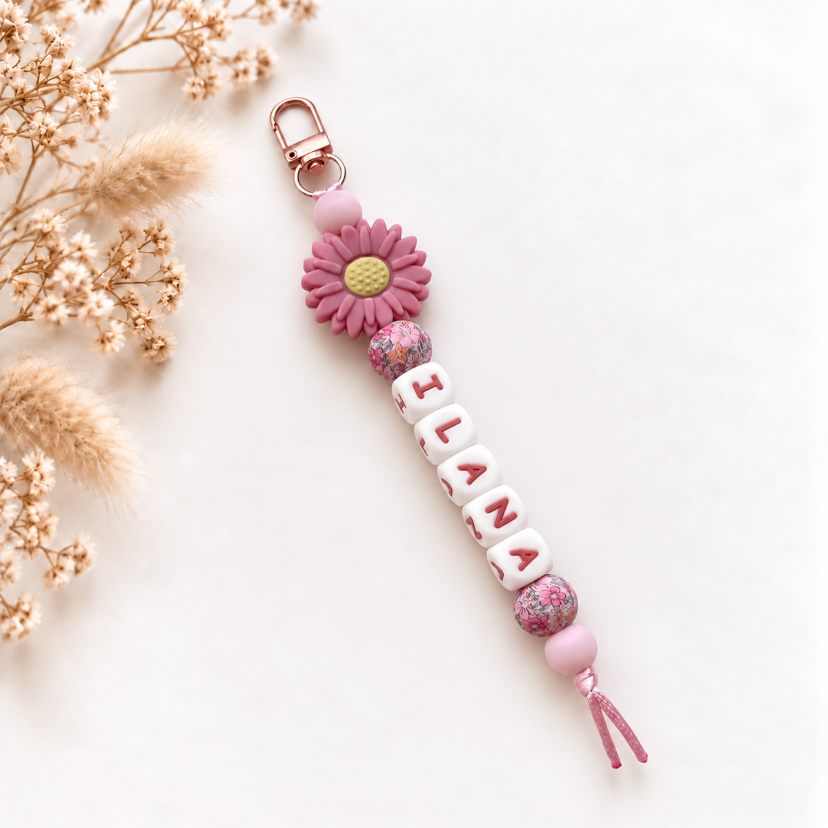 Handgemaakte roze sleutelhanger met naam en bloemdetail