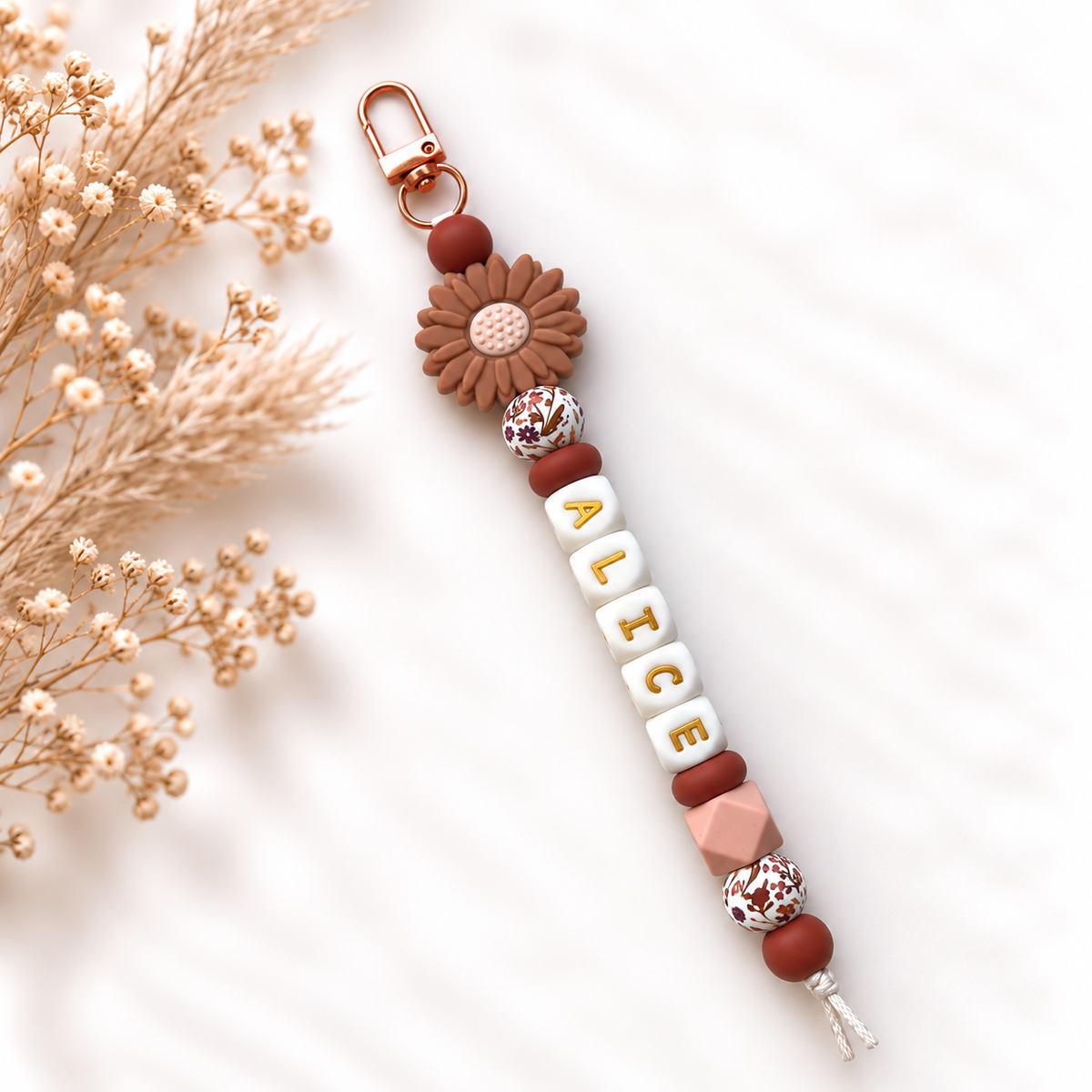 Handgemaakte sleutelhanger met naam in terracotta tinten en bloemdetail