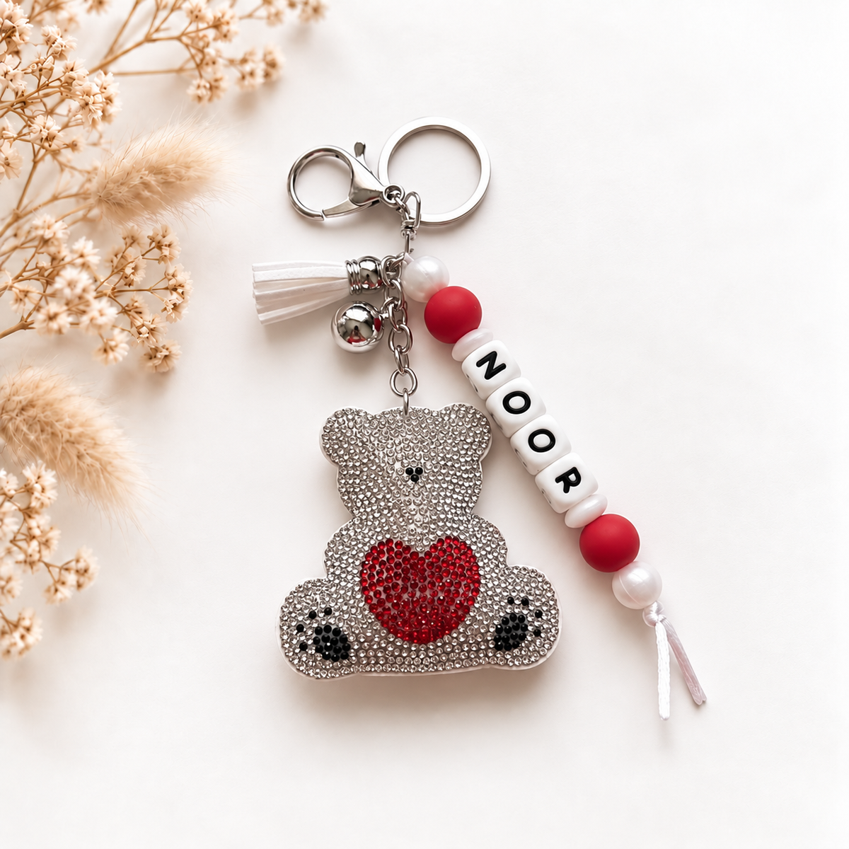 Handgemaakte sleutelhanger en tassenhanger met naam Noor en glinsterende teddybeer met rood hart