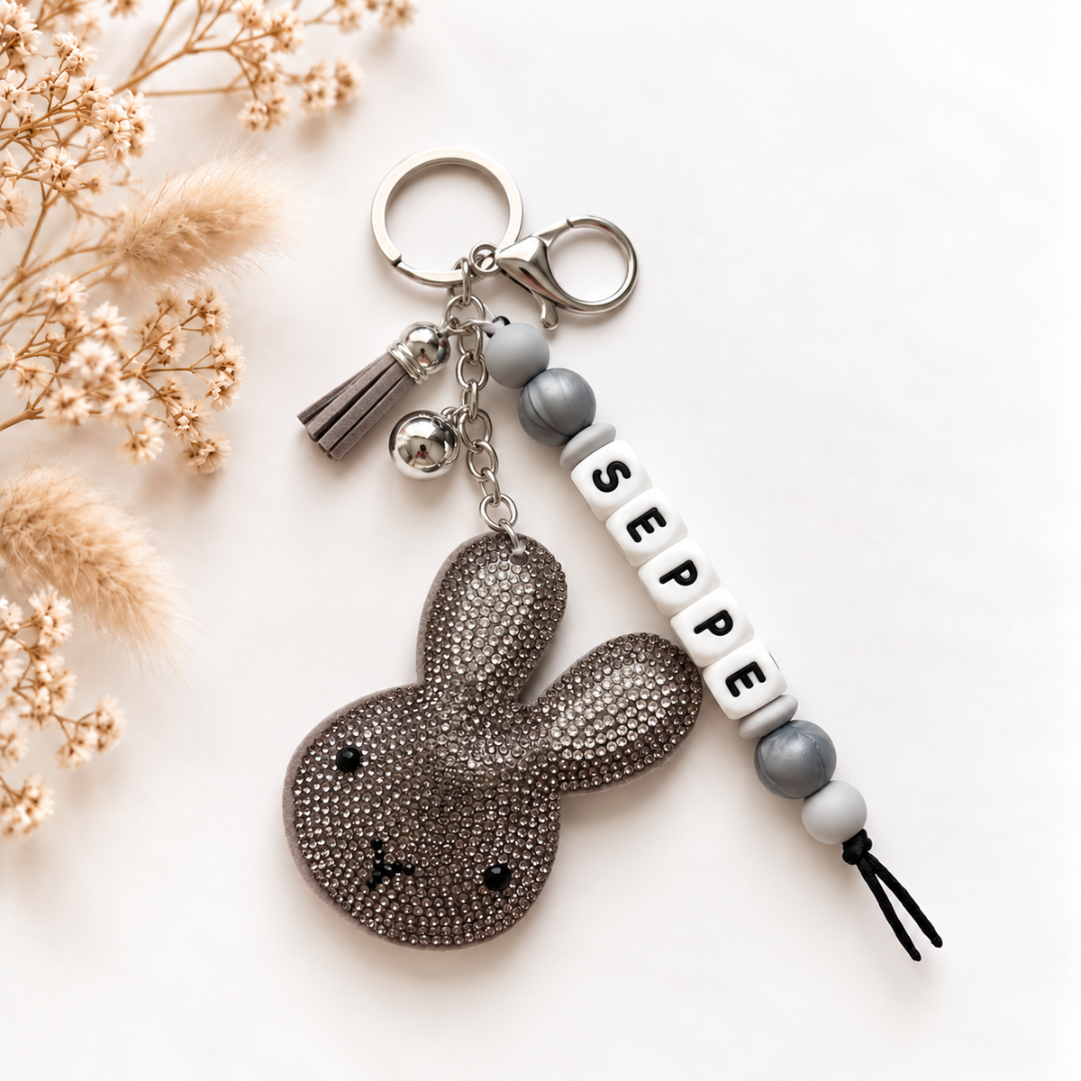 Handgemaakte sleutelhanger en tassenhanger met naam Seppe in grijs, wit en zilver met glinsterend detail