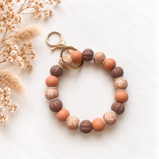 Sleutelwristlet Hazel Muse in warme bruine en café latte tinten met bloemenprint en parelachtige details