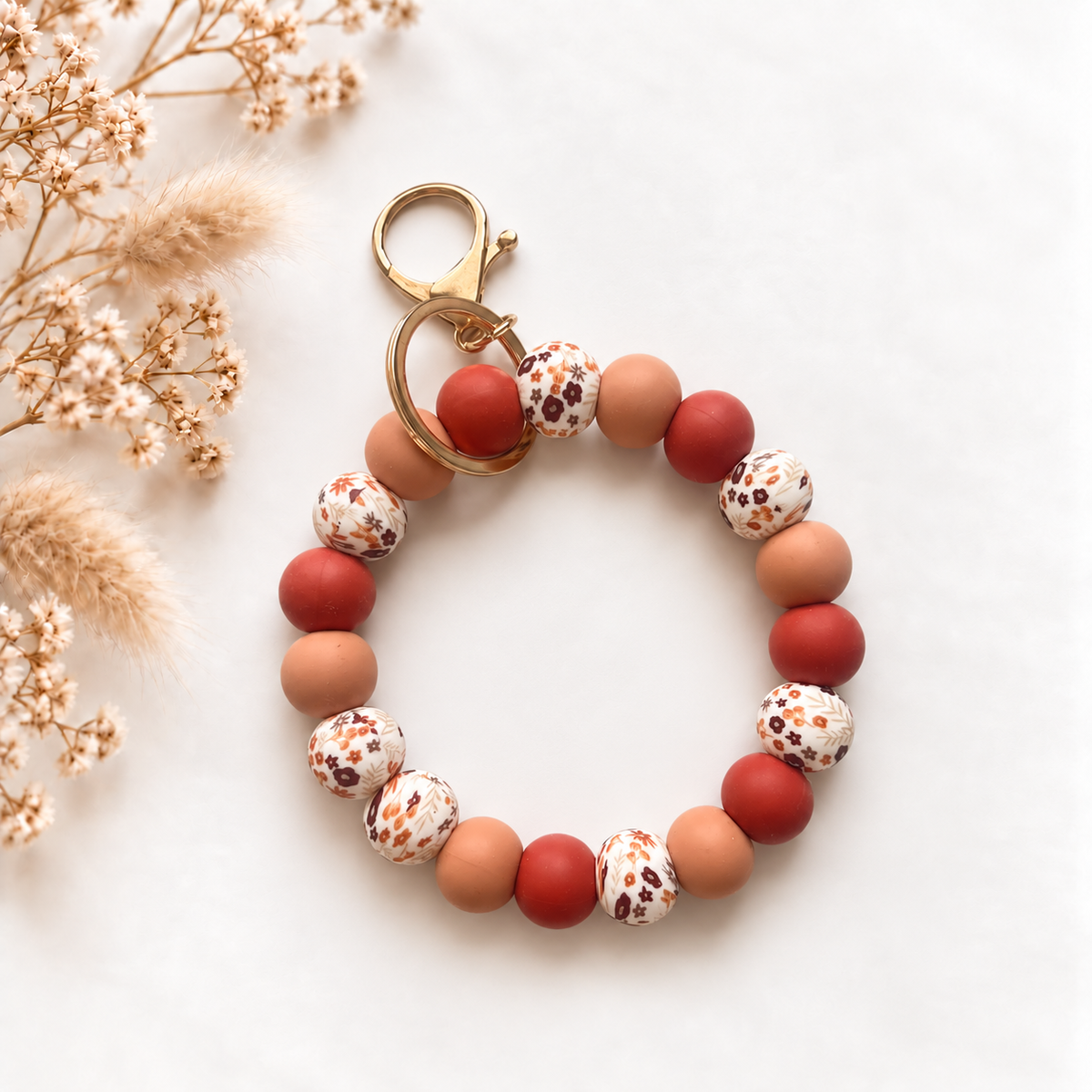 Sleutelwristlet Sienna Muse in warme rood- en perziktinten met bloemenprint en gouden details